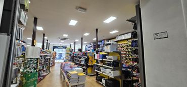 Intérieur d'une allée de magasin bien éclairée, avec des étagères remplies de marchandises et des cartons empilés au sol.