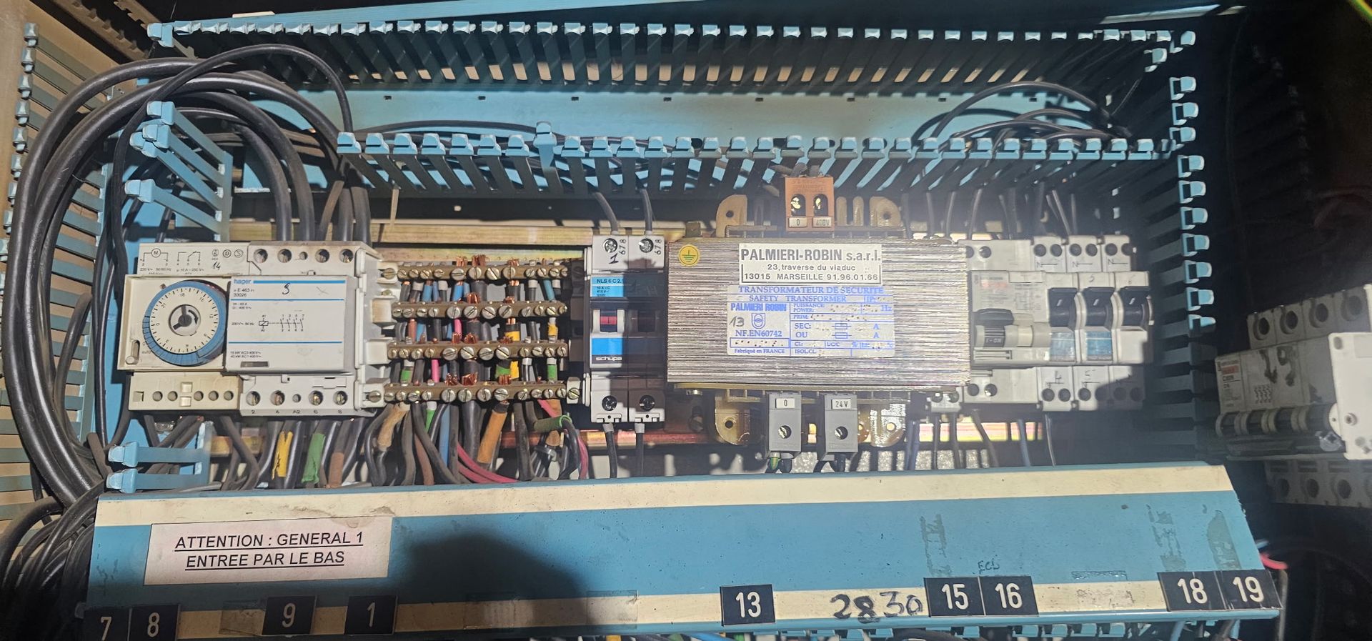 Panneau de commande électrique ouvert avec câblage, interrupteurs et composants de circuit dans une armoire métallique.