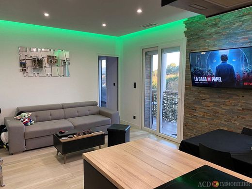 Salon moderne avec canapé d'angle gris, tables basses, télévision et éclairage d'ambiance LED vert