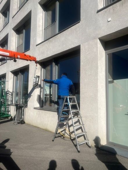 Un homme debout sur une échelle nettoyant une fenêtre