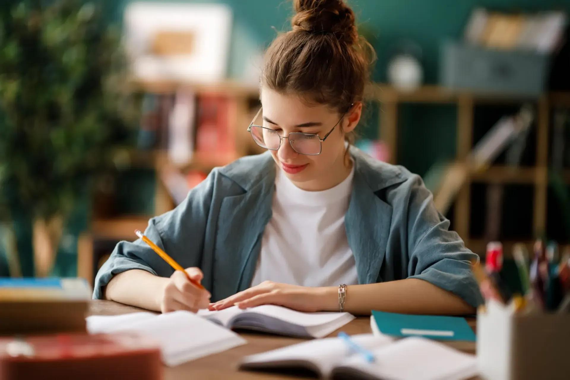 Una persona escribe en un cuaderno en un escritorio en un espacio de trabajo con iluminación tenue