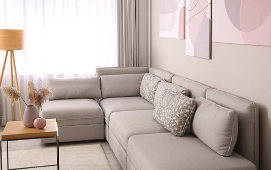 Una sala de estar con un sofá, una mesa, una lámpara y cuadros en la pared.