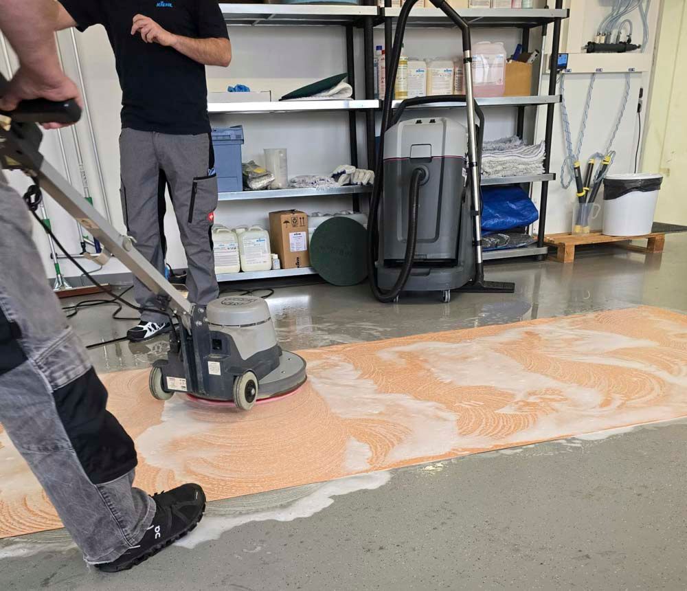 Ein Mann poliert mit einer Maschine einen Teppich