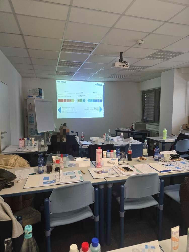 Ein Klassenzimmer mit Tischen und Stühlen sowie einer Projektionsleinwand.