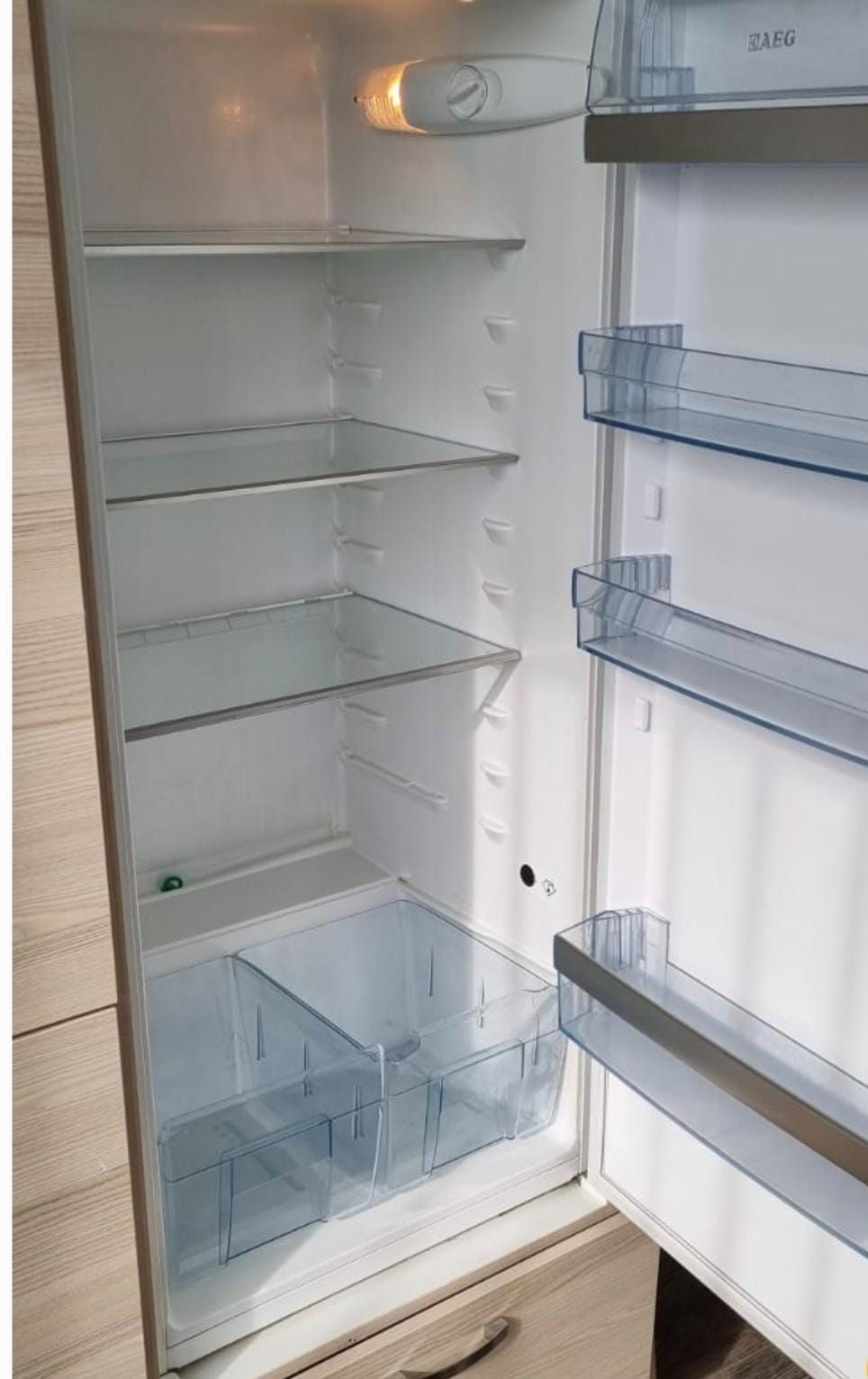 Das Innere eines leeren Kühlschranks mit geöffneter Tür.