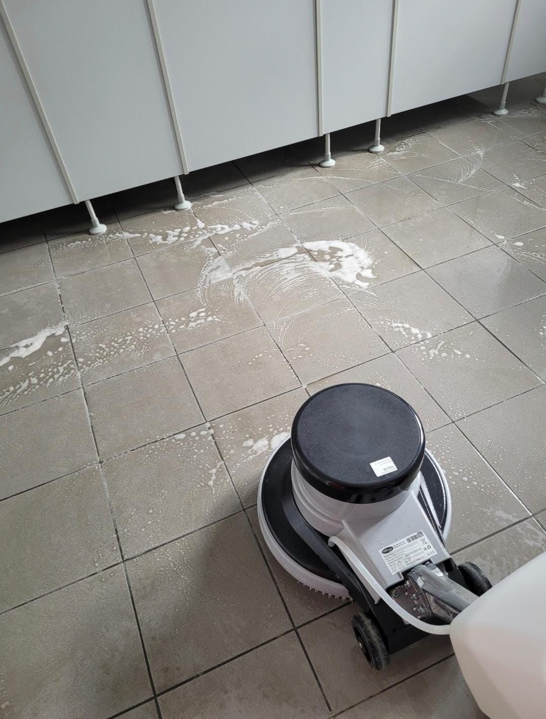 Eine Maschine reinigt einen gefliesten Boden in einem Badezimmer.