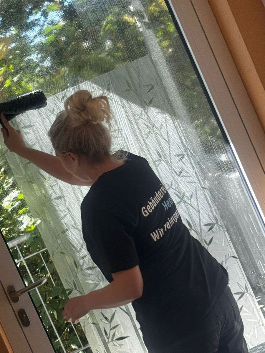 Eine Frau putzt ein Fenster mit einer Sprühflasche.