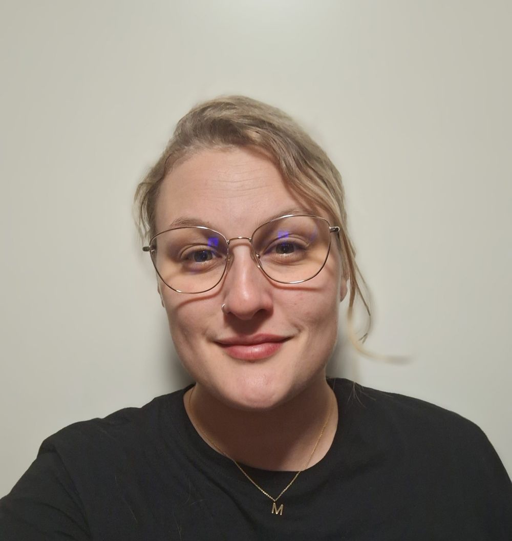 Eine Nahaufnahme einer Frau mit Brille und einer Tätowierung auf der Brust.