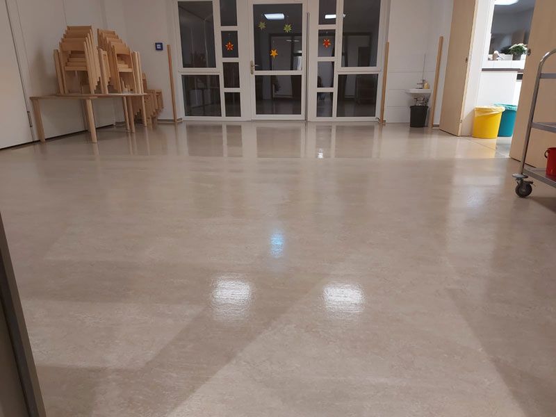 Ein großer Raum mit glänzendem Boden und ein paar Stühlen auf einem Tisch.