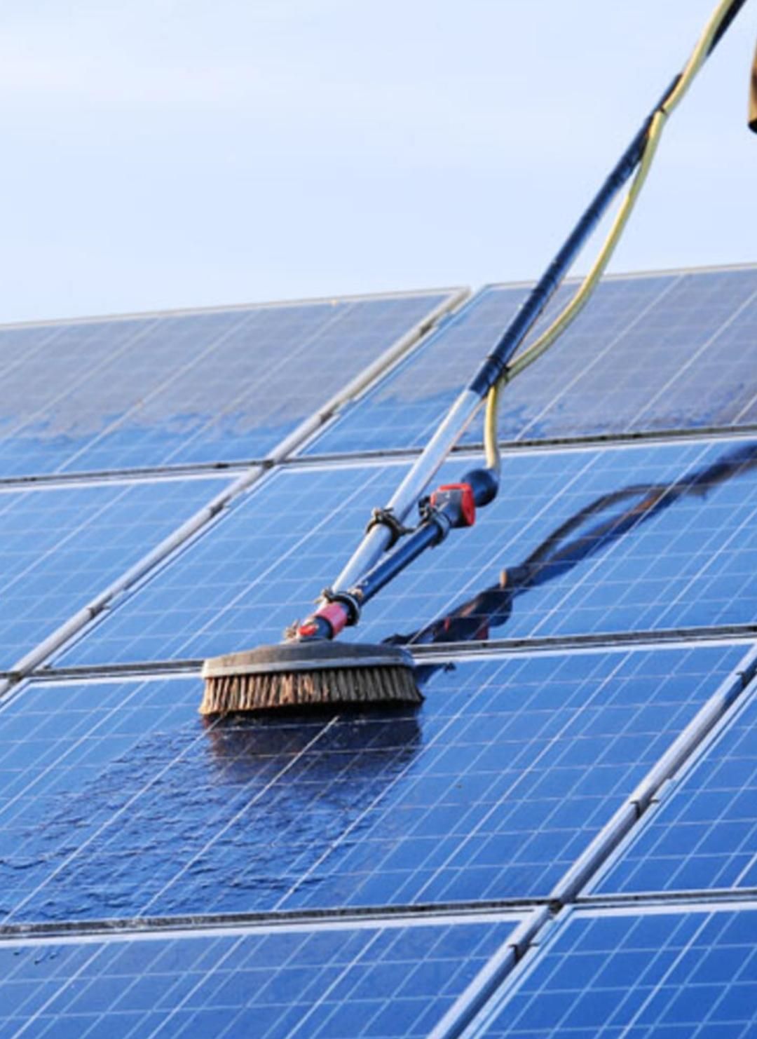 Bürstenreinigung blauer Solarmodule unter klarem Himmel