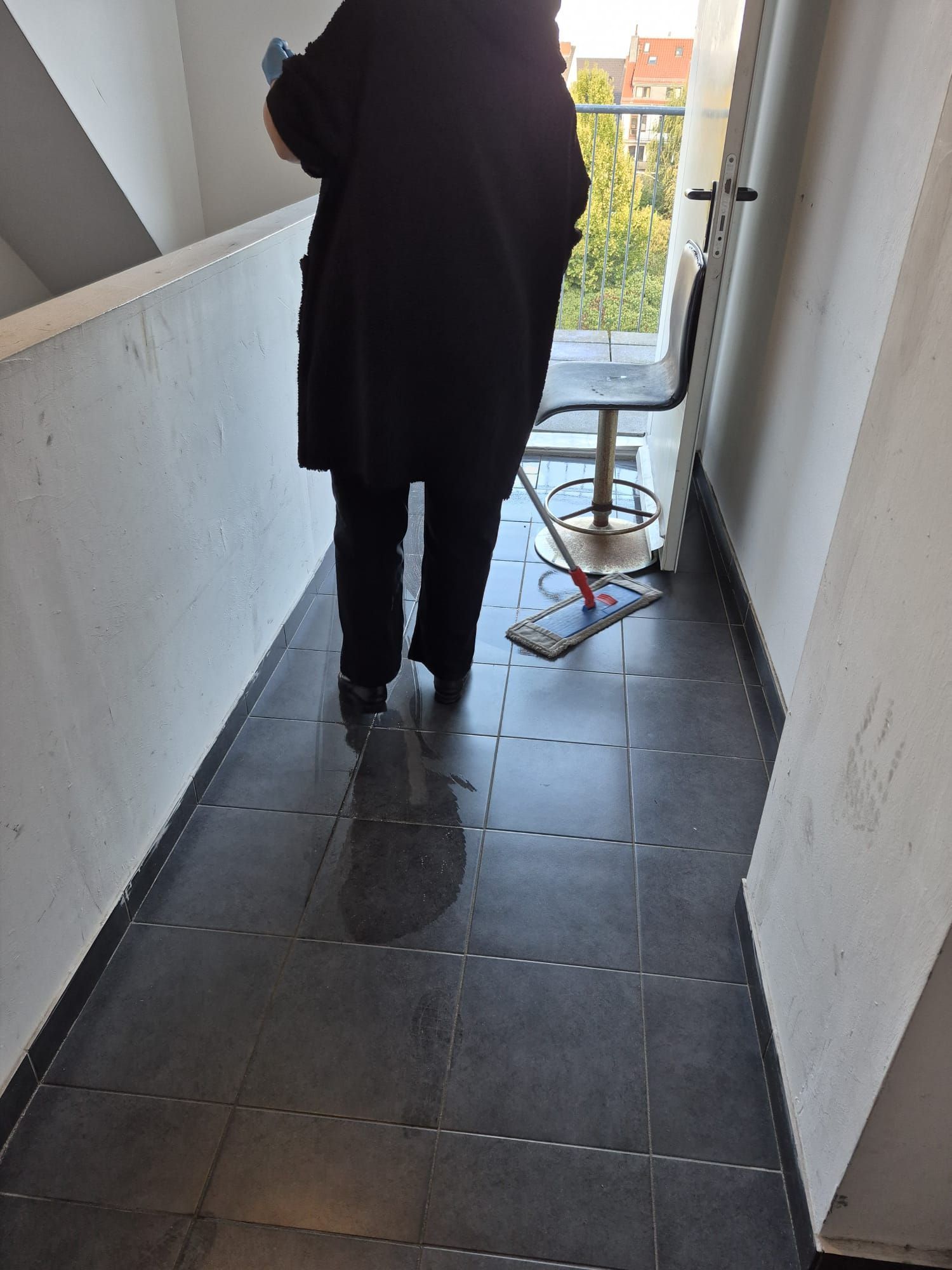 Eine Person geht von hinten gesehen einen schmalen Flur entlang, an dessen Ende ein Wagen steht.