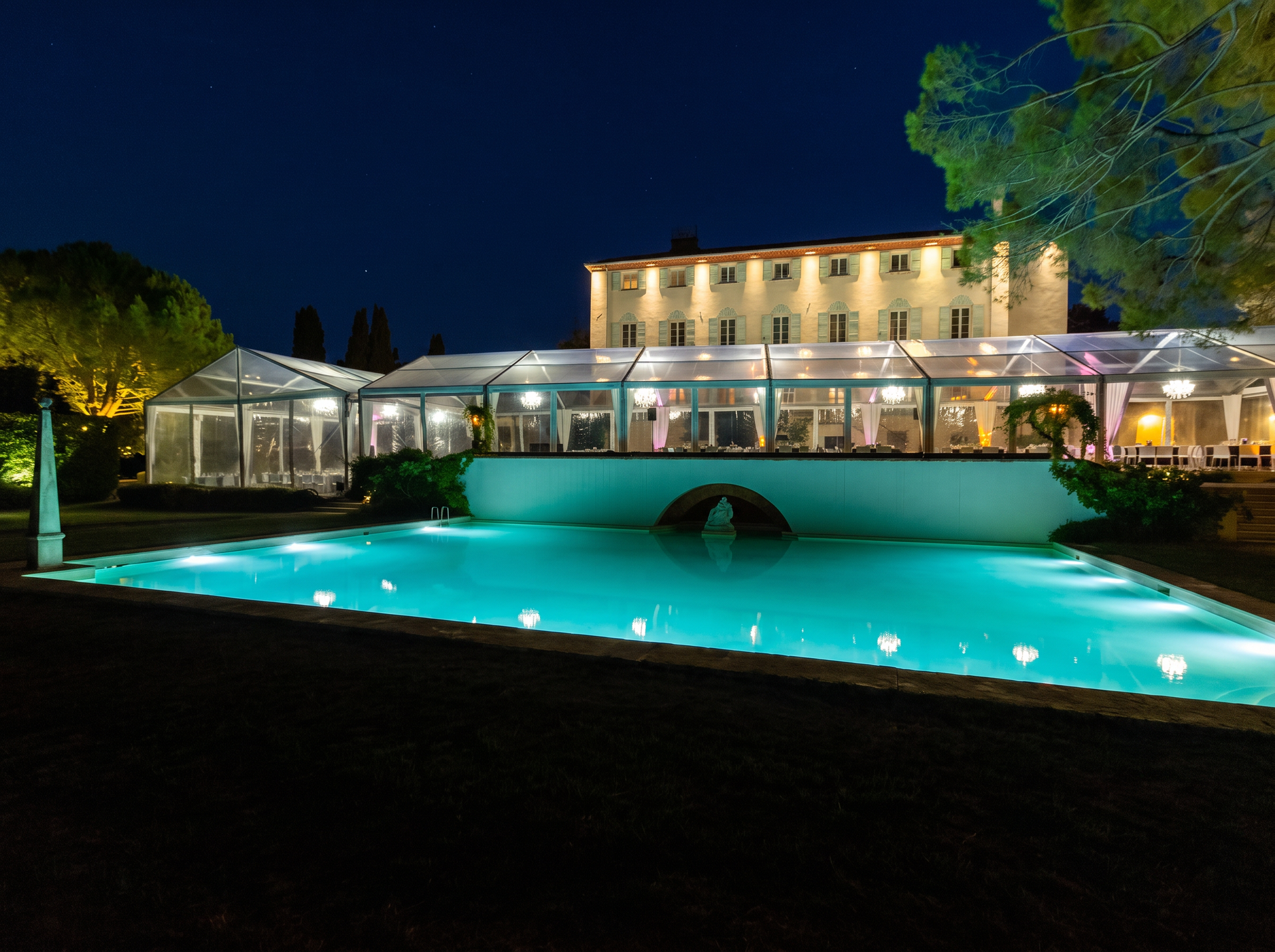Vue aérienne d'un complexe, avec une piscine et des tentes au crépuscule