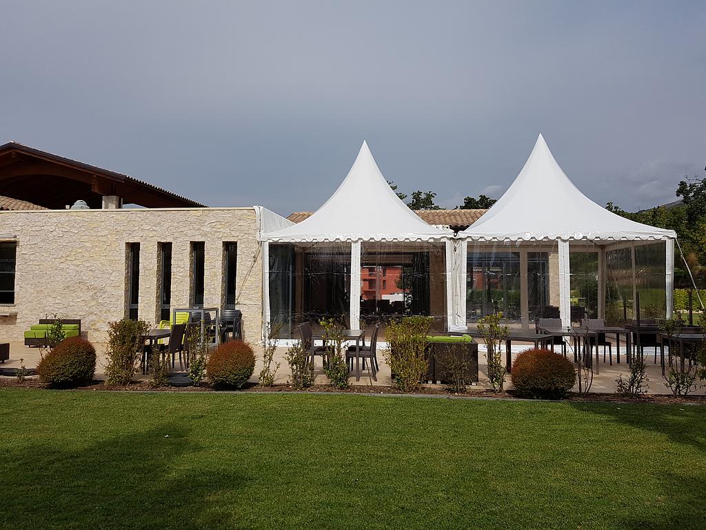 Bâtiment moderne avec deux tentes blanches, une terrasse et une pelouse