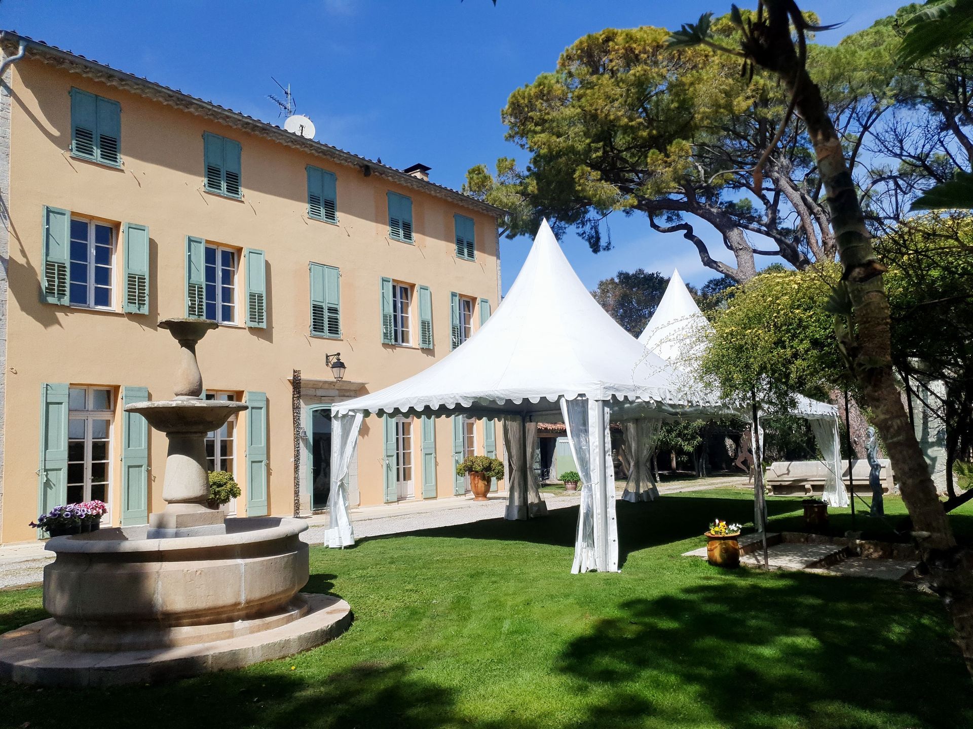 Cour intérieure avec un bâtiment beige, une fontaine et un barnum blanc pour événements