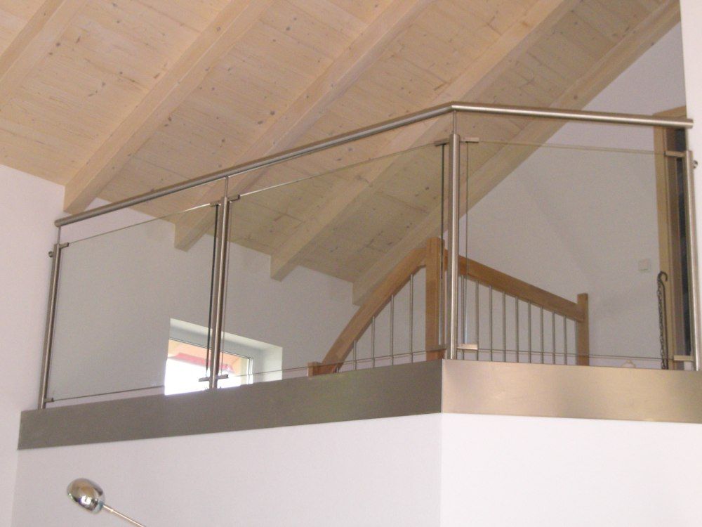 Loftbalkon mit Glasgeländer, Holzdecke und Treppe in einem hellen Interieur