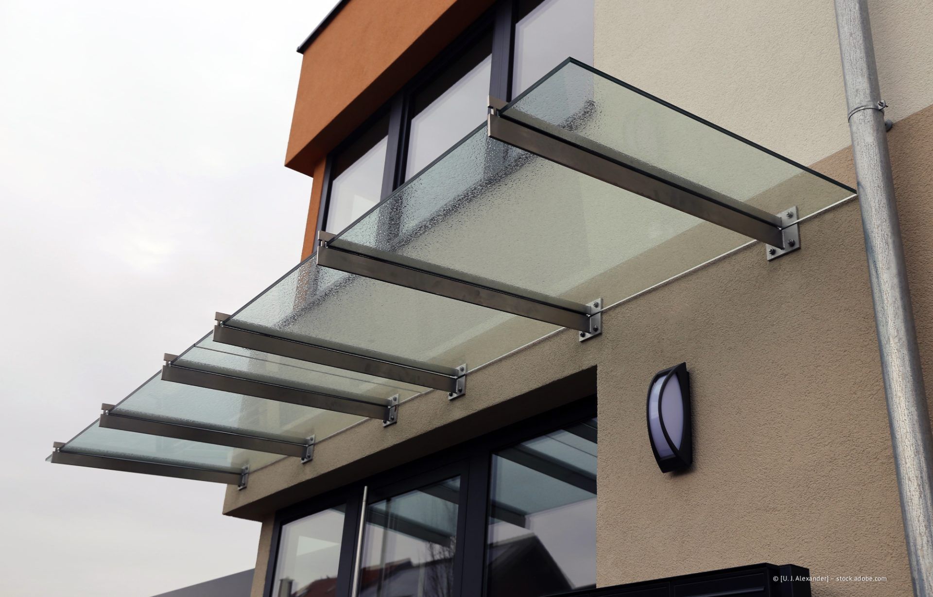 Moderne Gebäudefassade mit einem Glas-Metall-Vordach über dem Eingang