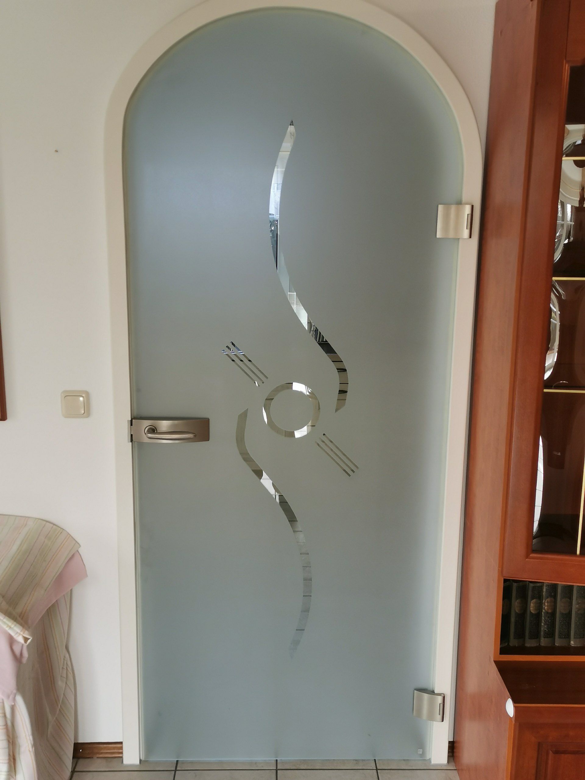 Gewölbte, mattierte Glastür mit wellenförmigem Ätzmuster im Wohnbereich.