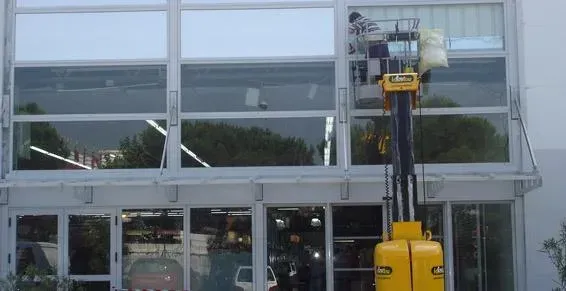 Professionnel sur un élévateur qui pose un film de protection sur une fenêtre