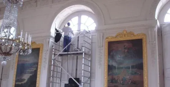 Professionnel sur un échafaudage qui pose un film sur une fenêtre en demi-cercle