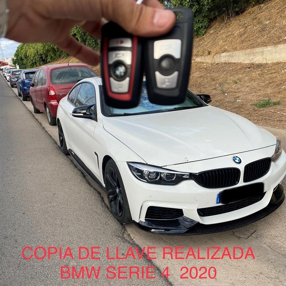 Mano sosteniendo dos llaves de coche sobre un BMW Serie 4 2020 blanco. En la carretera. Texto: «Copia de llave realizada».