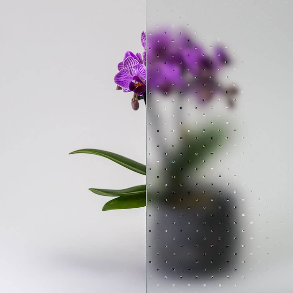 Lila Orchideenpflanze hinter strukturiertem Glas.