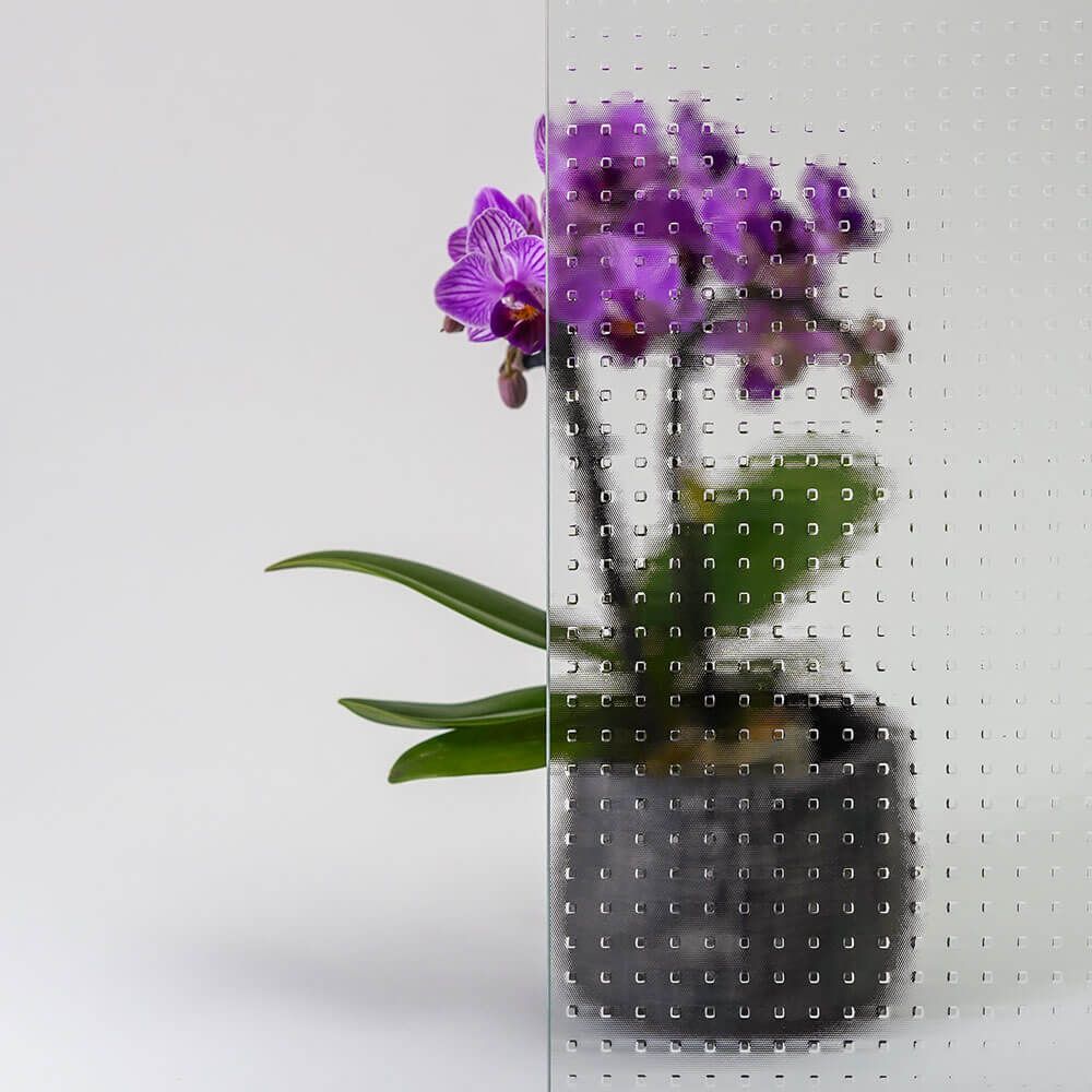 Lila Orchideenpflanze hinter strukturiertem Glas.