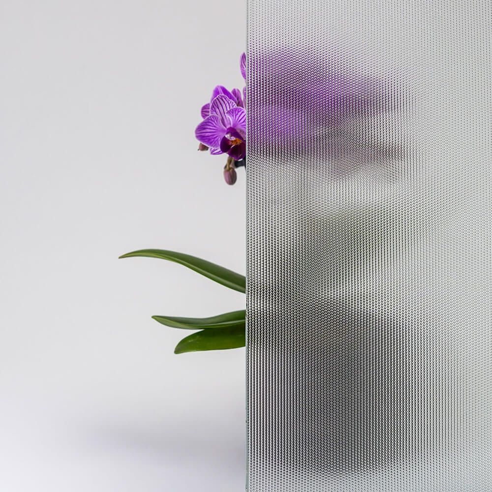 Orchidee mit violetten Blüten hinter einer strukturierten, gemusterten Glasscheibe.