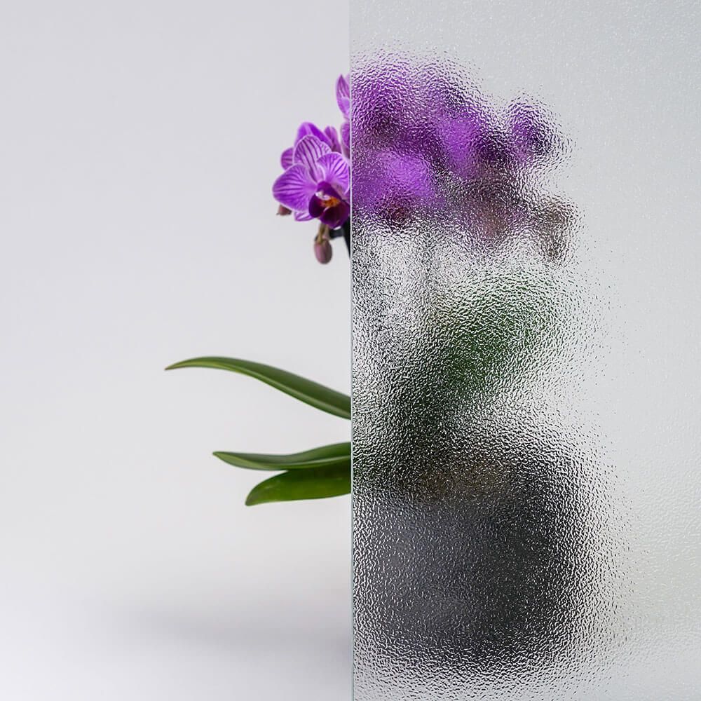 Eine violette Orchidee hinter strukturiertem Glas, wodurch die Details der Pflanze verschwimmen.