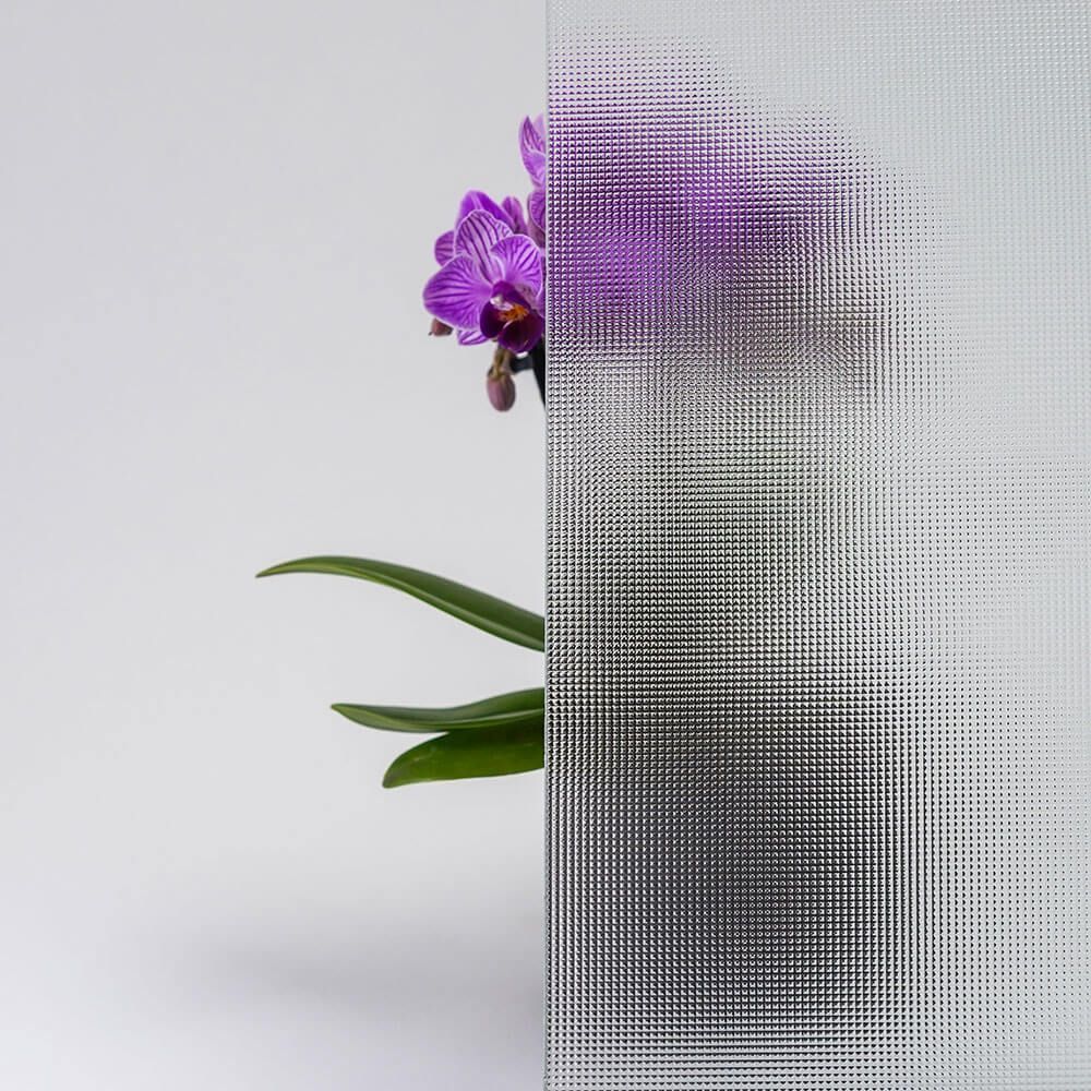 Lila Orchidee und grüne Blätter hinter Milchglas.