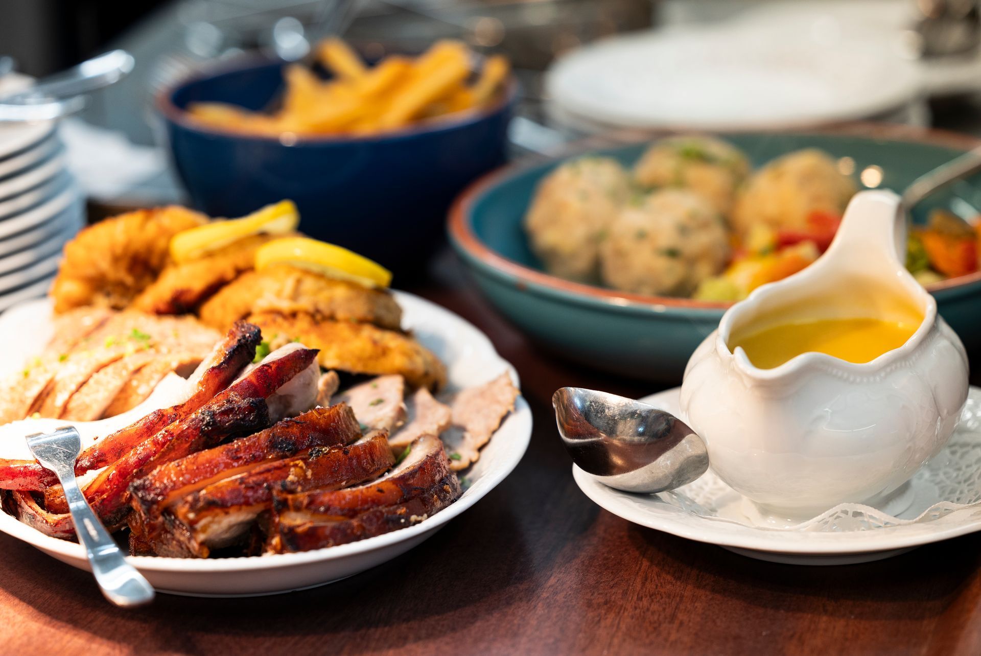 Restauranttisch im Freien mit Brezeln, Bier und Vorspeisen; sonniger Tag.