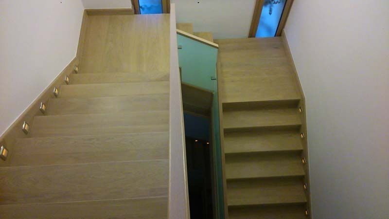 Una escalera de madera con barandilla de cristal en una casa.