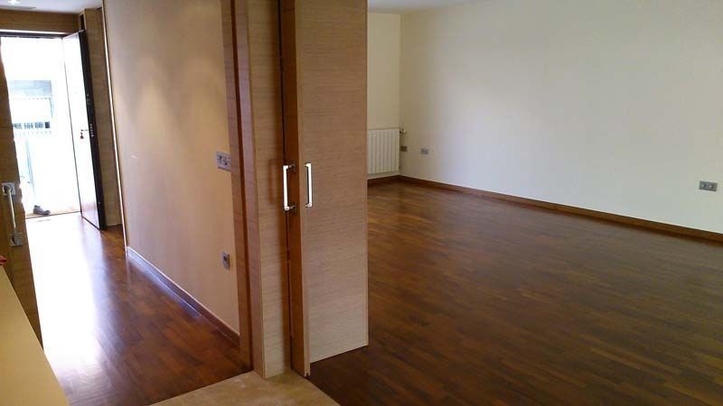 Una habitación vacía con suelo de madera y paredes blancas.