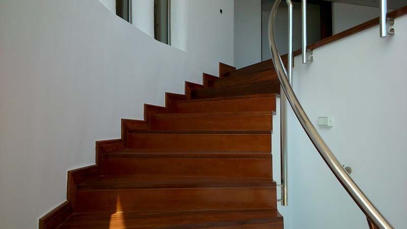 Una escalera de madera con barandilla de acero inoxidable