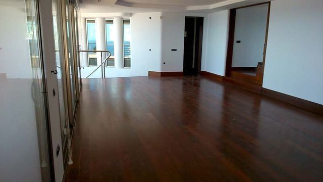 Una habitación vacía con pisos de madera y paredes blancas.