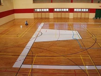 Una gran cancha de baloncesto de madera con un cuadrado blanco en el medio