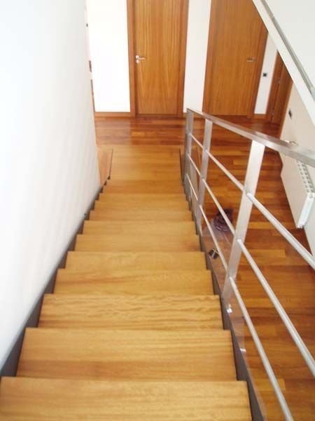 Una escalera de madera con barandilla de acero inoxidable
