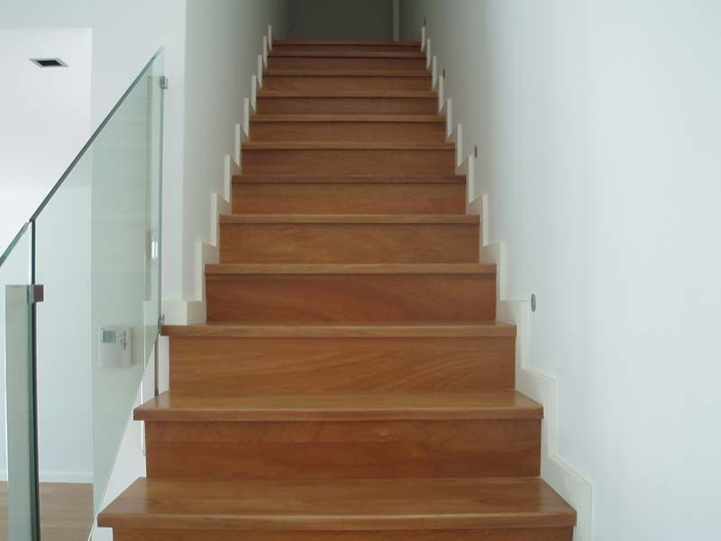 Un conjunto de escaleras de madera con barandilla de vidrio.