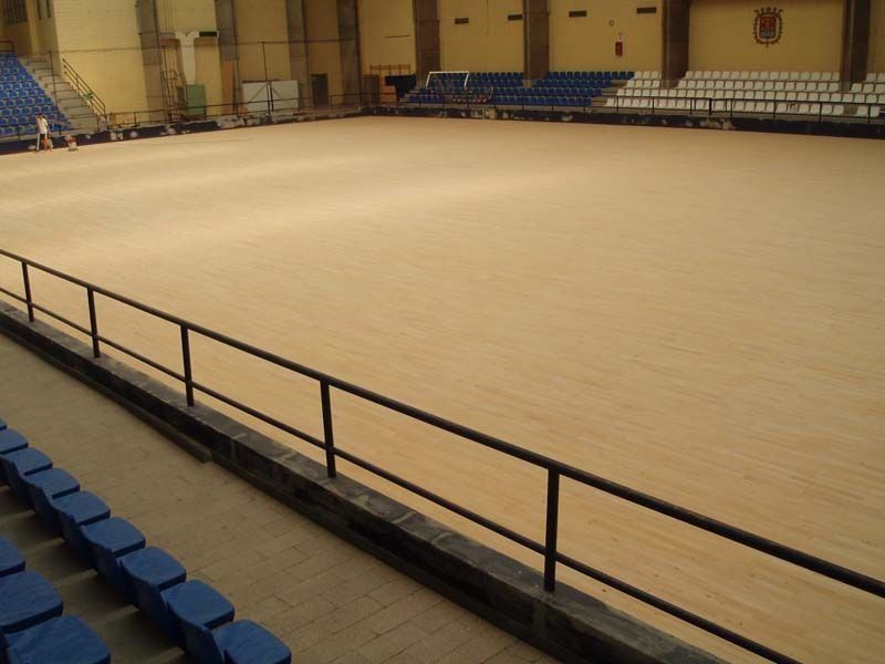 Un estadio vacío con asientos azules y suelo de madera.