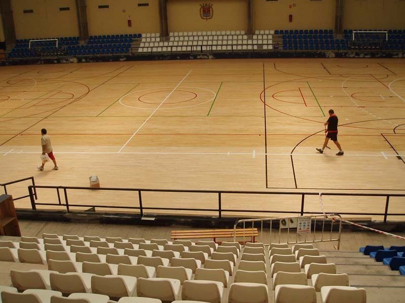 Dos hombres están jugando al baloncesto en un estadio vacío.