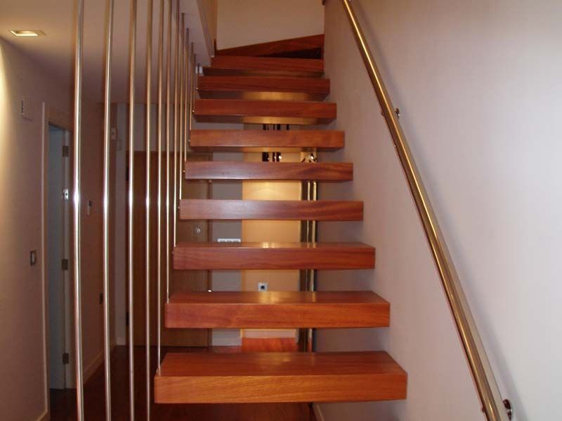 Una escalera de madera con barandilla de acero inoxidable