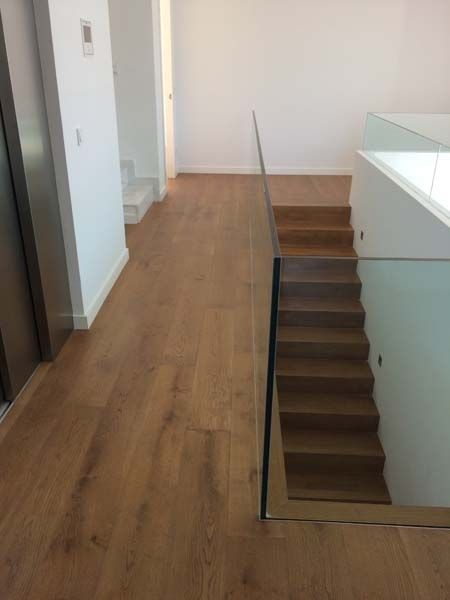 Una escalera de madera con barandilla de cristal en una habitación.