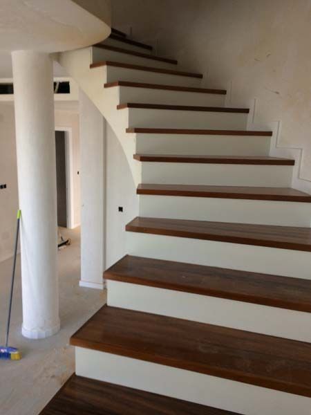 Una escalera blanca con escalones de madera en una habitación.