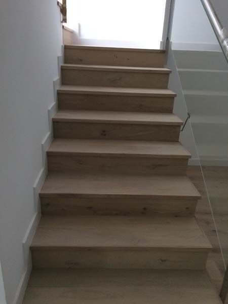 Las escaleras son de madera y tienen barandilla de cristal.