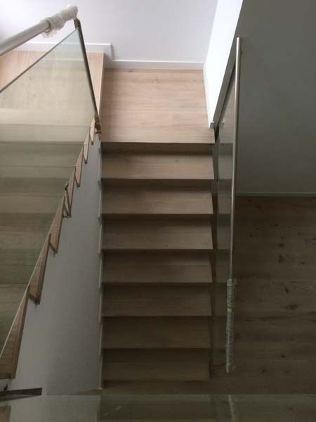 Una escalera de madera con barandilla de cristal en una casa.
