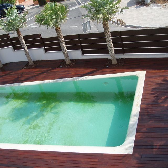 Una piscina rodeada de palmeras y una terraza de madera.