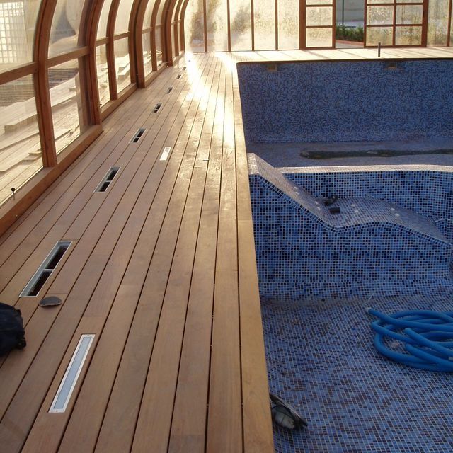 Una piscina con una plataforma de madera que la rodea.