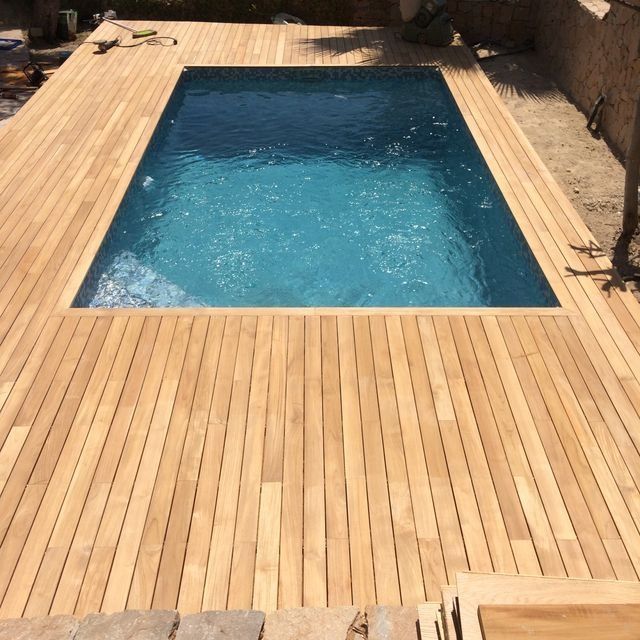 Una gran piscina está rodeada por una terraza de madera.
