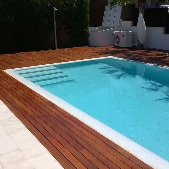 Una gran piscina rodeada por una terraza de madera.