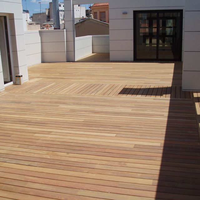 Una terraza de madera con una puerta al fondo.