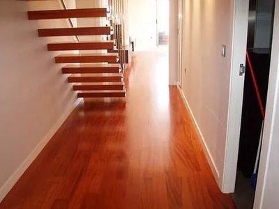 Un pasillo con pisos de madera y escaleras al fondo.